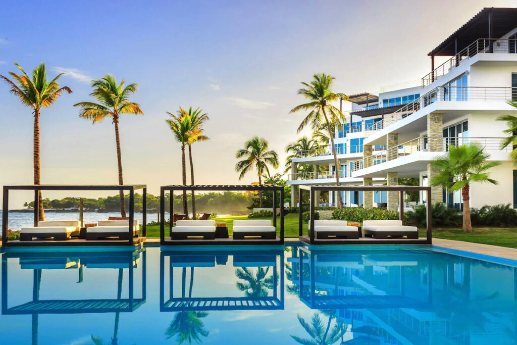 The outdoor swimming pool area with beds and palm trees at a beachfront resort in the Dominican Republic.