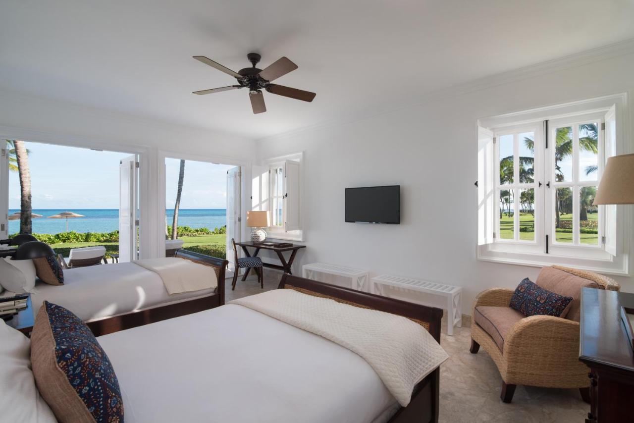 A resort bedroom in the Dominican Republic with two beds, other furniture, and view of the sea.