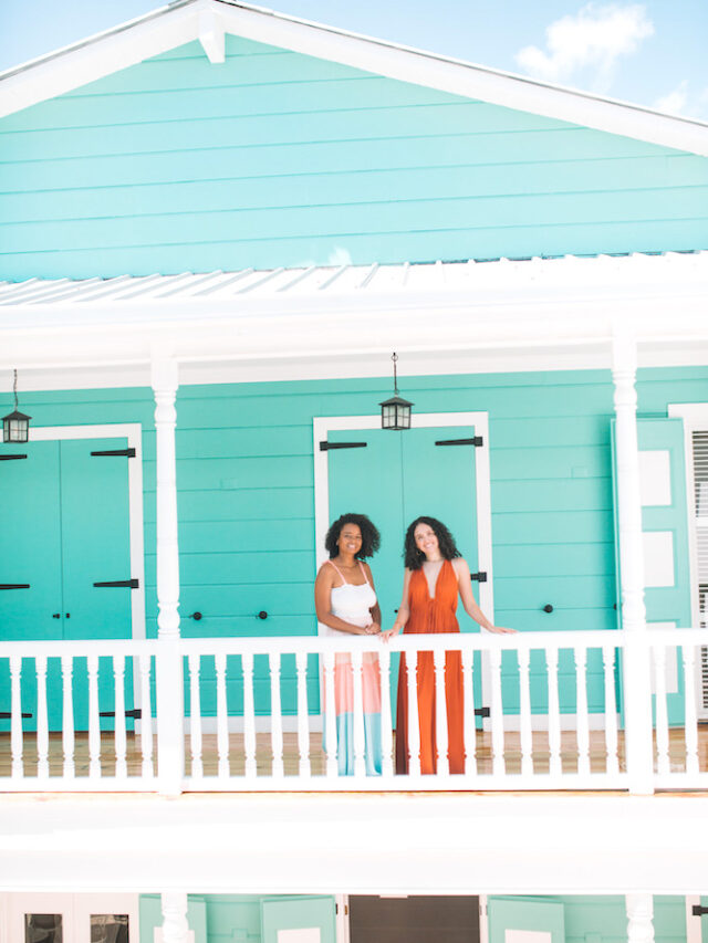 Two women on a city tour in Puerto Plata standing on the outdoor area of the second floor of a green building.