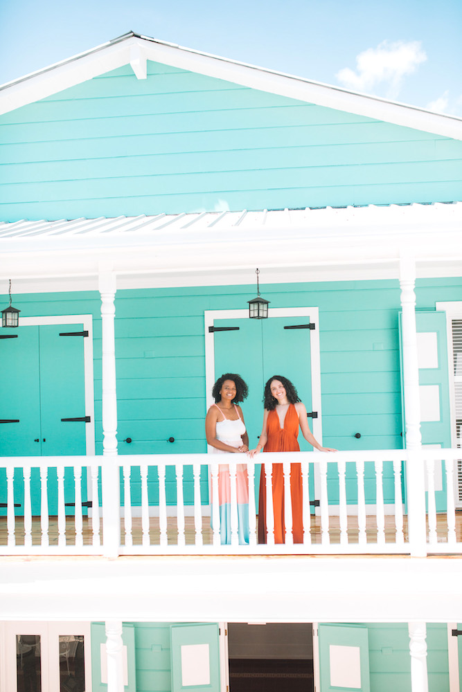 Two women at the outdoor area of the second story of a green-and-white building in Puerto Plata.