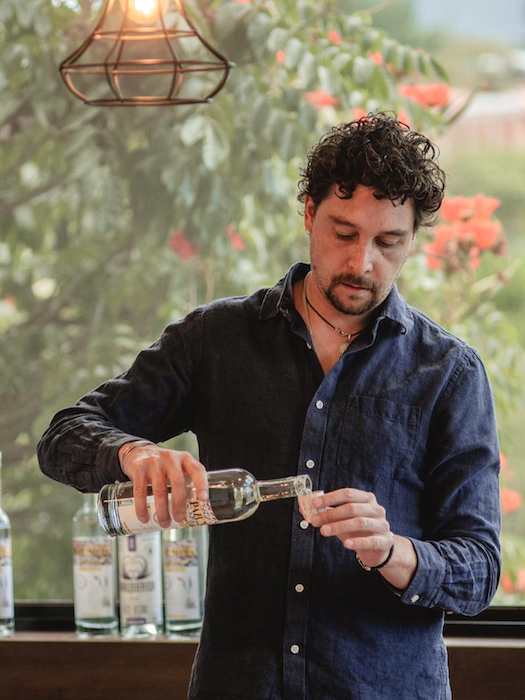 A man puring. adrink to a small glass.