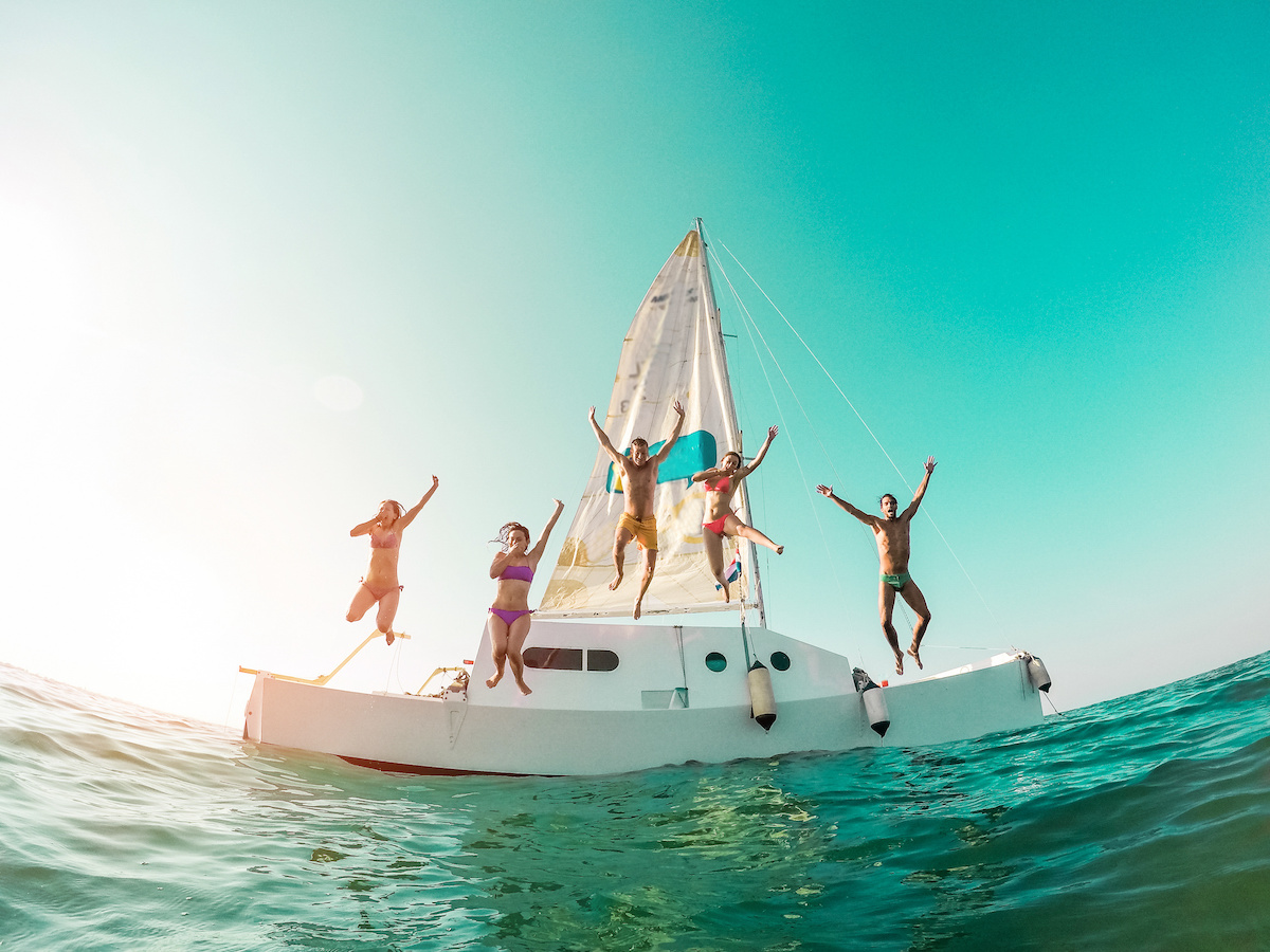 Five people jumping into water from a boat.