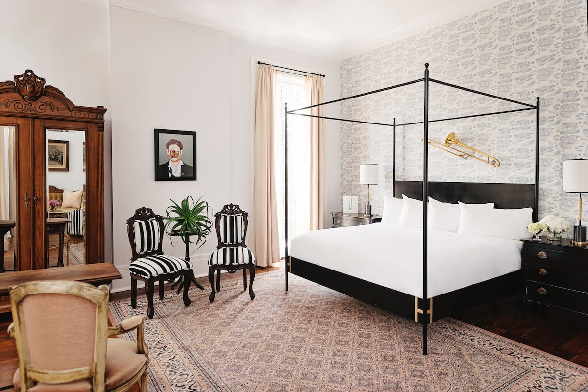 A fancy bedroom with furniture, carpet, artwork, and musical instrument in a boutique hotel in New Orleans.