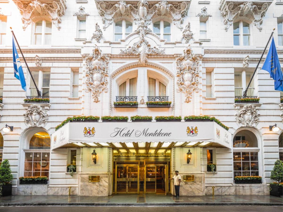 The entrance of a hotel with flags and French-inspired architecture.