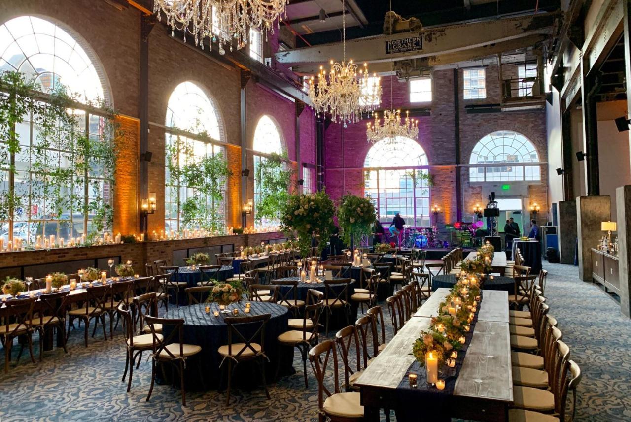 A carpeted dining hall of a hotel in New Orleans with rectangular tables, circular tables, chairs, chandeliers, and plants.