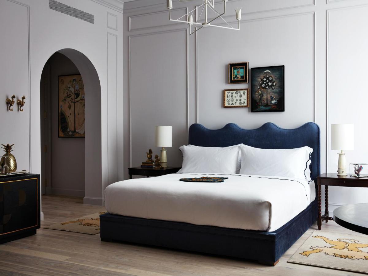 White bed with blue bed frame in a white-painted bedroom in one of the boutique hotels in New Orleans.