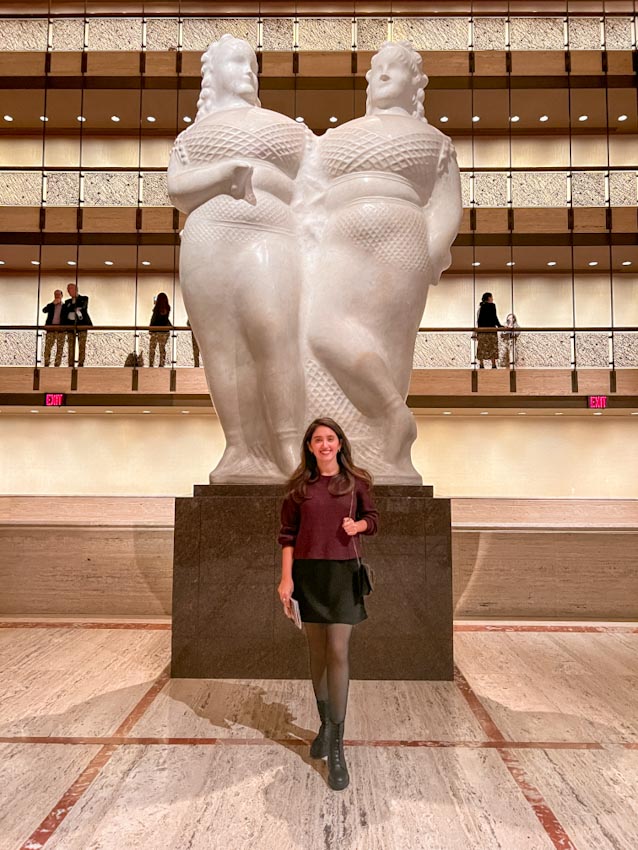 A woman standing by a statue inside the Lincoln Center, New York City in December