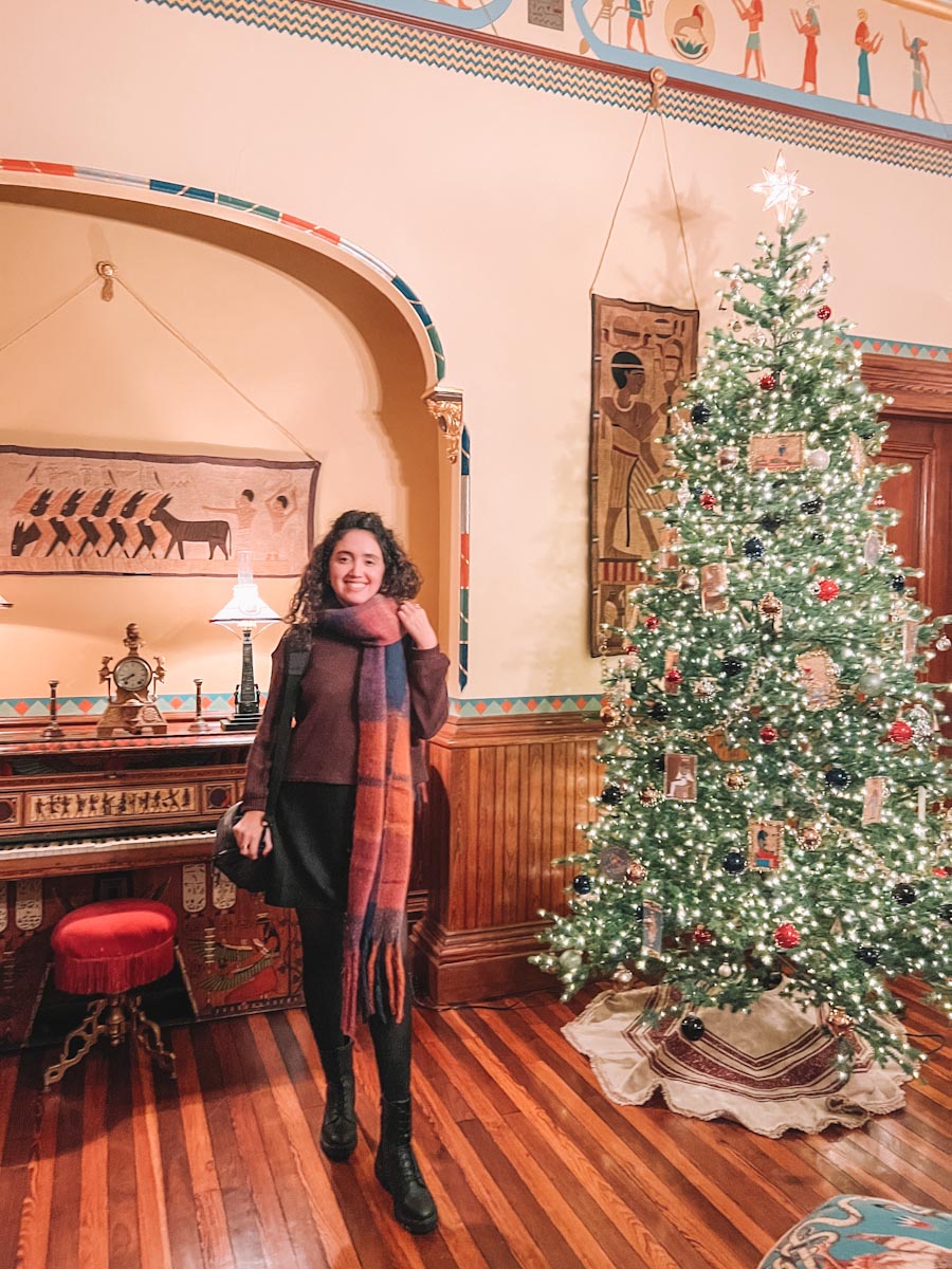 A woman standing by a Christmas tree inside the Octagon House