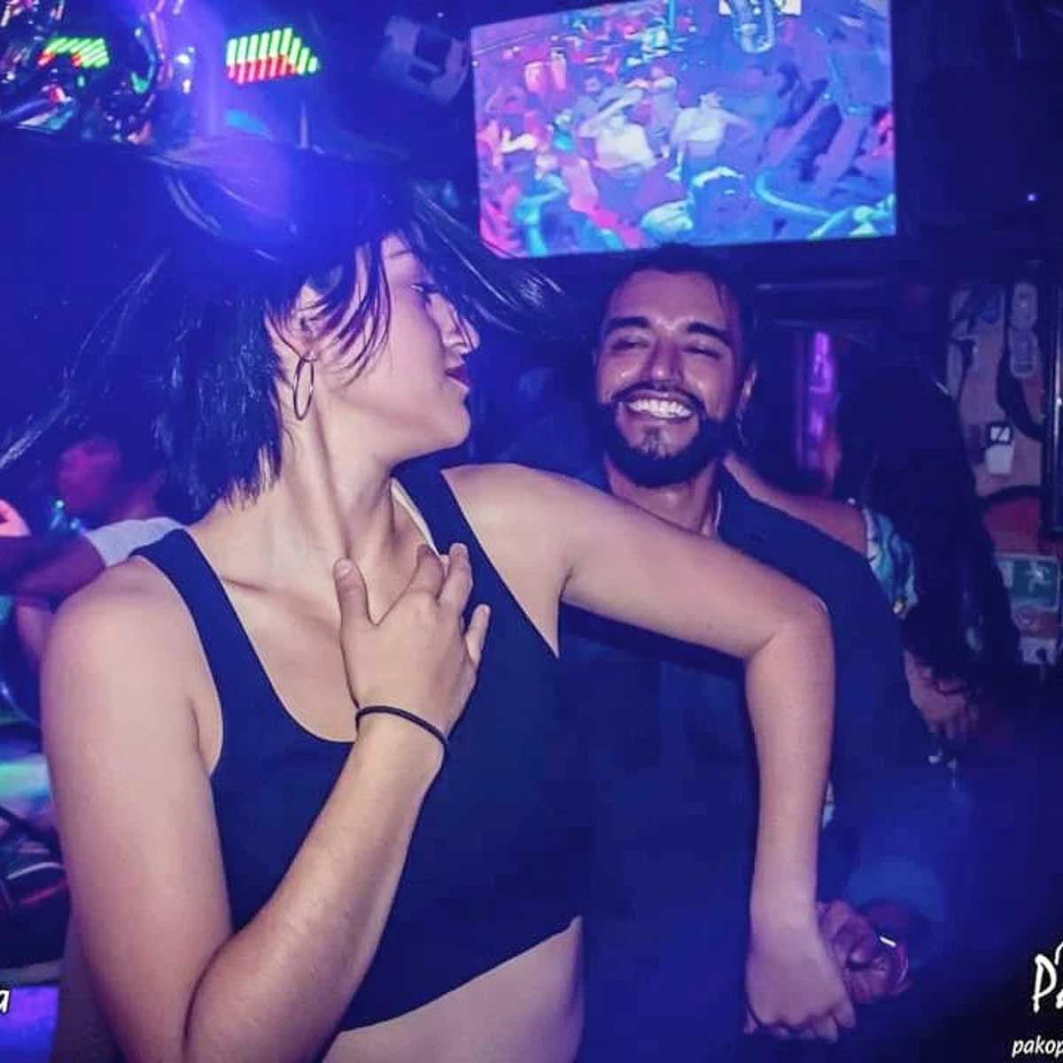 A man and a woman in a bar doing salsa dance