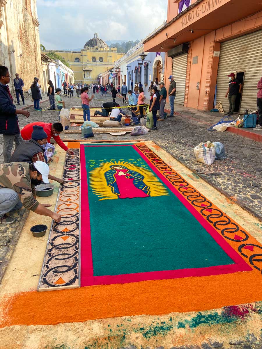 People creating colorful and intricate carpets on a street in celebration of Las Alfombras in Antigua, Guatemala