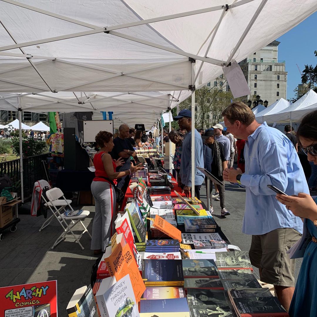 People interacting between displayed books at the Brooklyn Book Festival