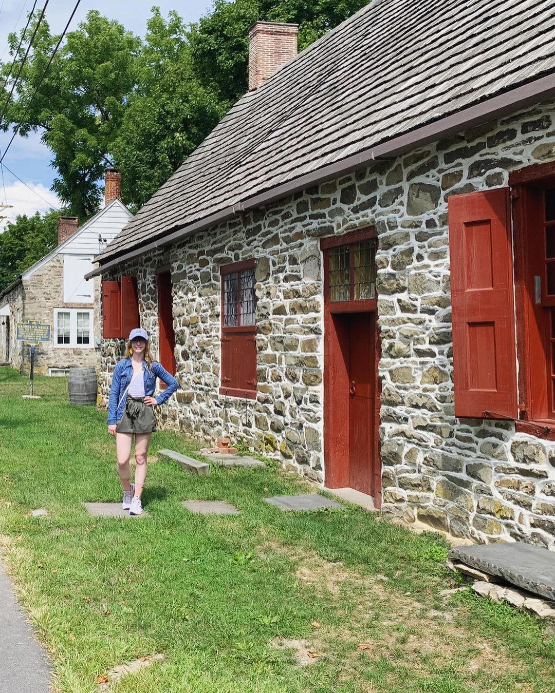 A girl standing in front of a house on the Historic Huguenot Street in New Paltz
