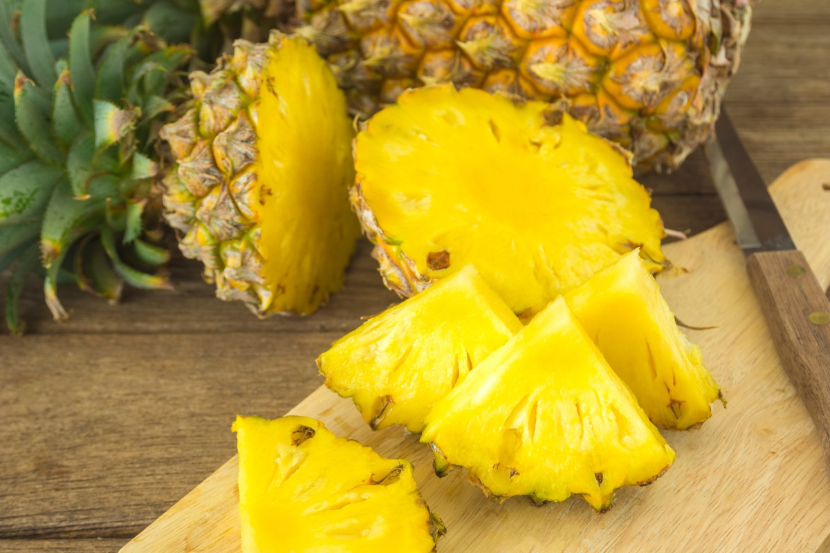 Whole and sliced pineapples on a wooden surface