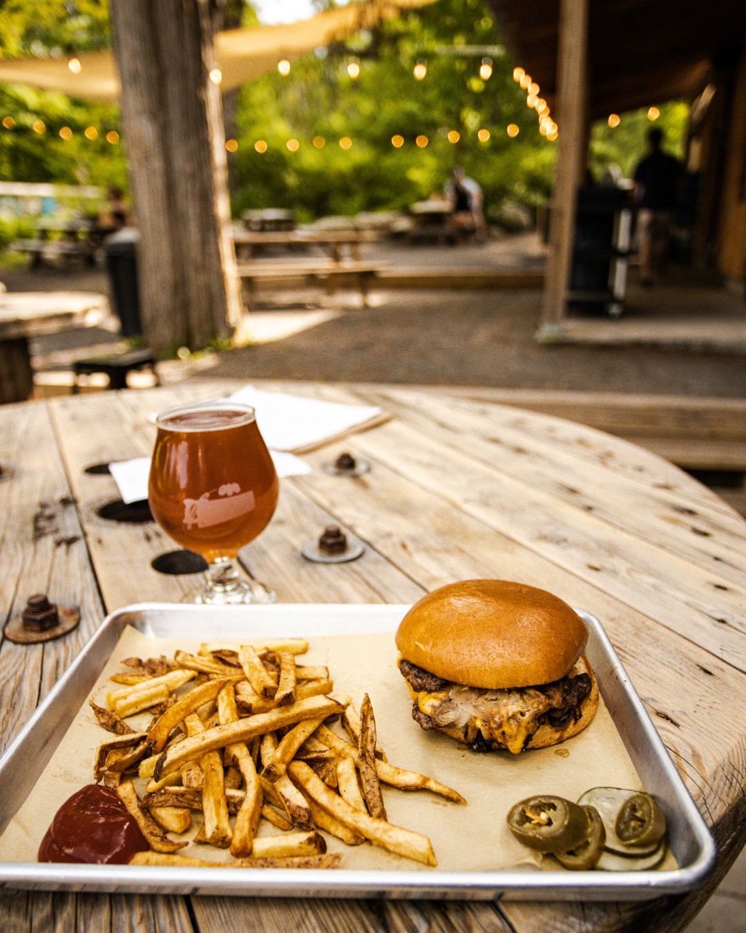 A burger, fries, and a drink on a wooden table at Rough Cut Brewing in New Paltz, New York