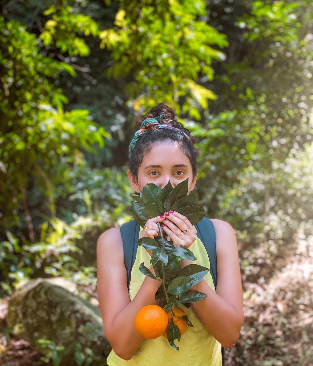 A woman holding naranja agria or sour oranges stems with fruits attached to it