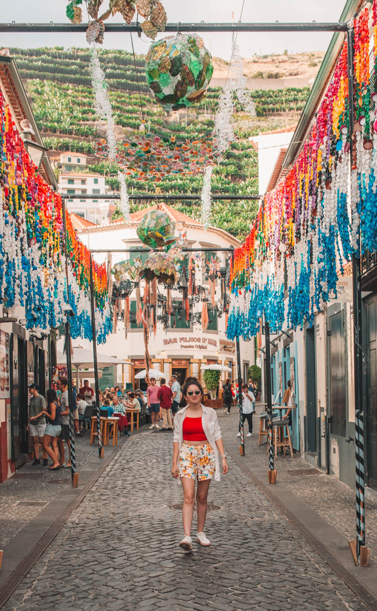 A woman walking on a colorful Camara de Lobos street in Madeira, Portugal