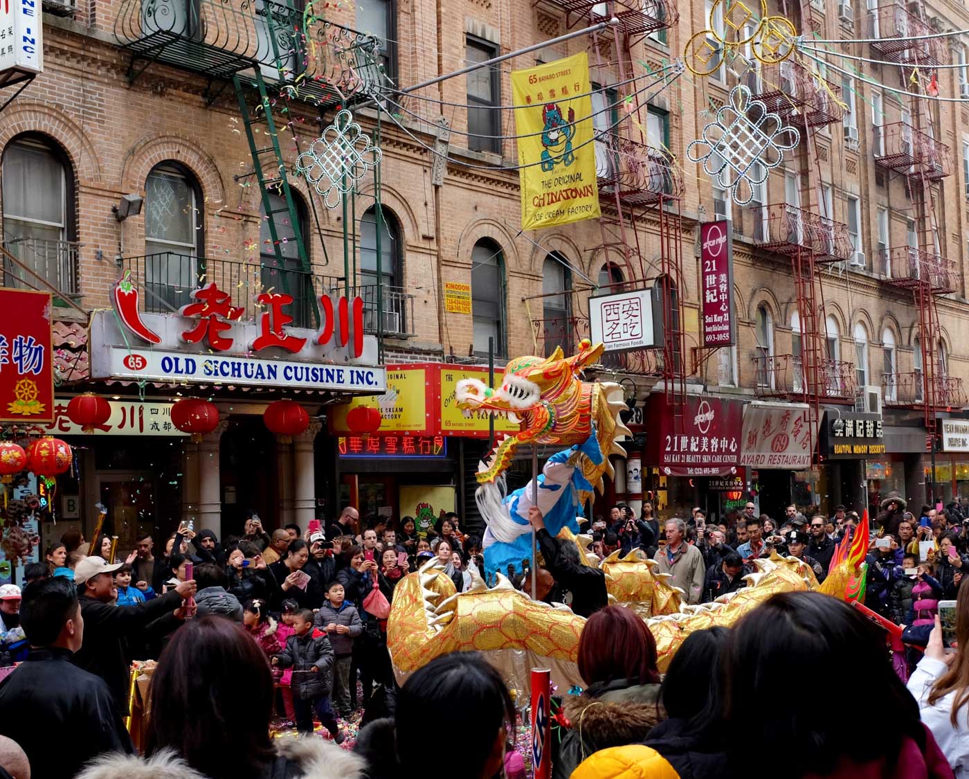 People watching a Chinese New Year dragon dance parade on a street in Chinatown, NYC in January