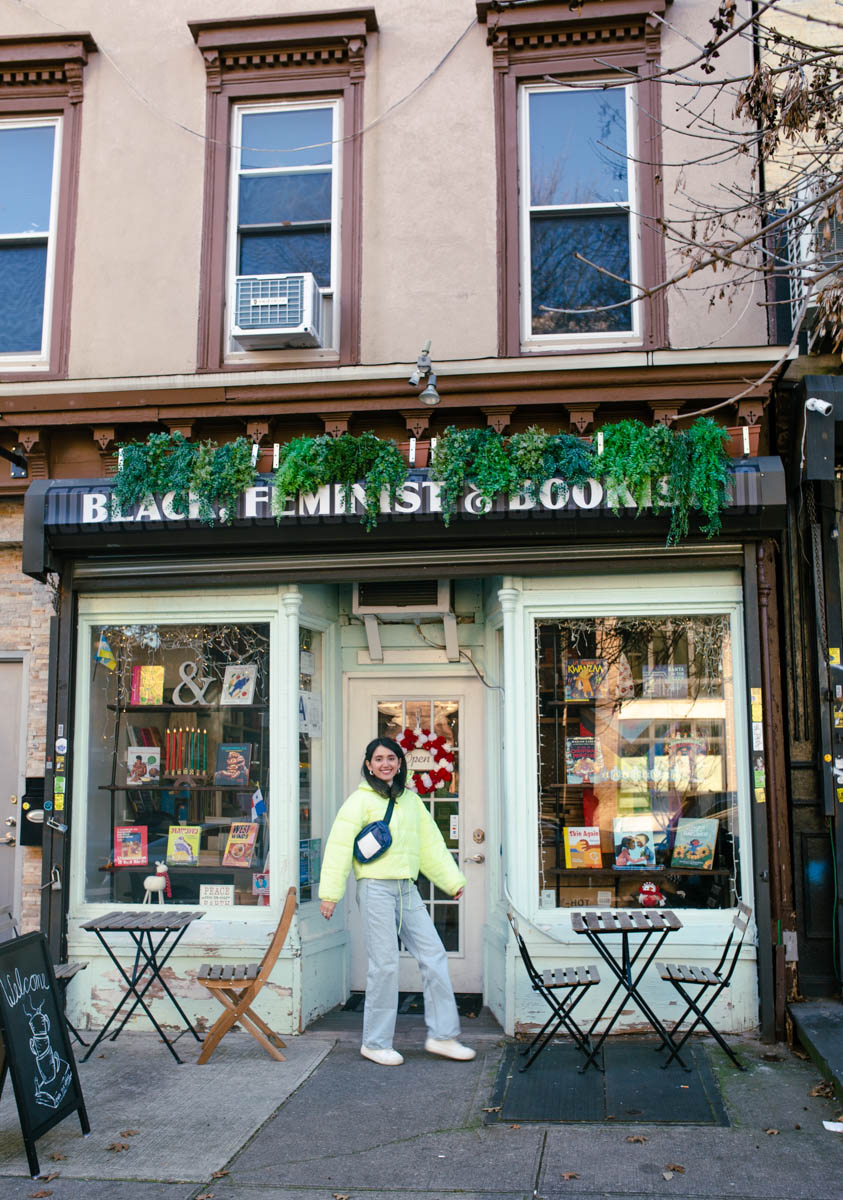 A woman standing at the outside entrance of Cafe con Libros in New York City