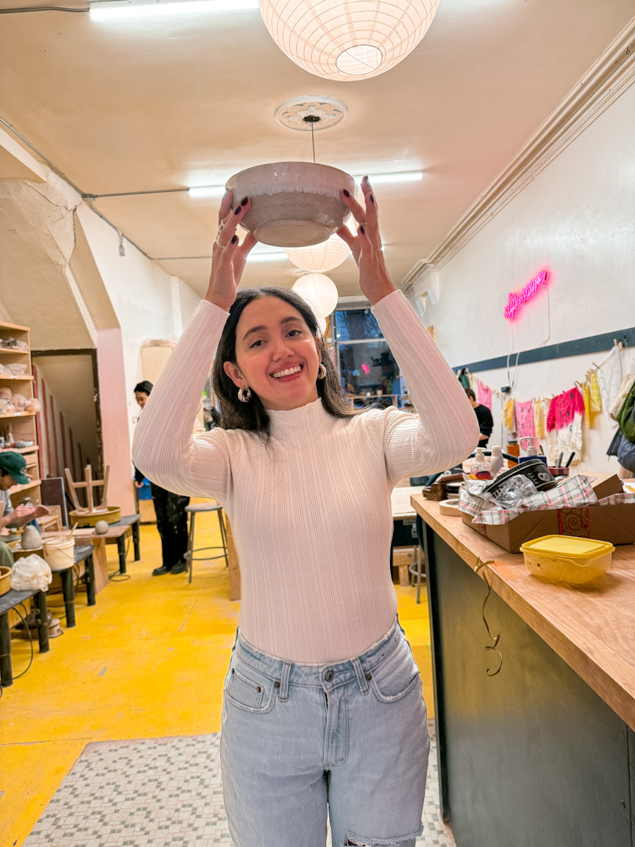 A woman in white top and jeans holding a bowl at Artshack Brooklyn