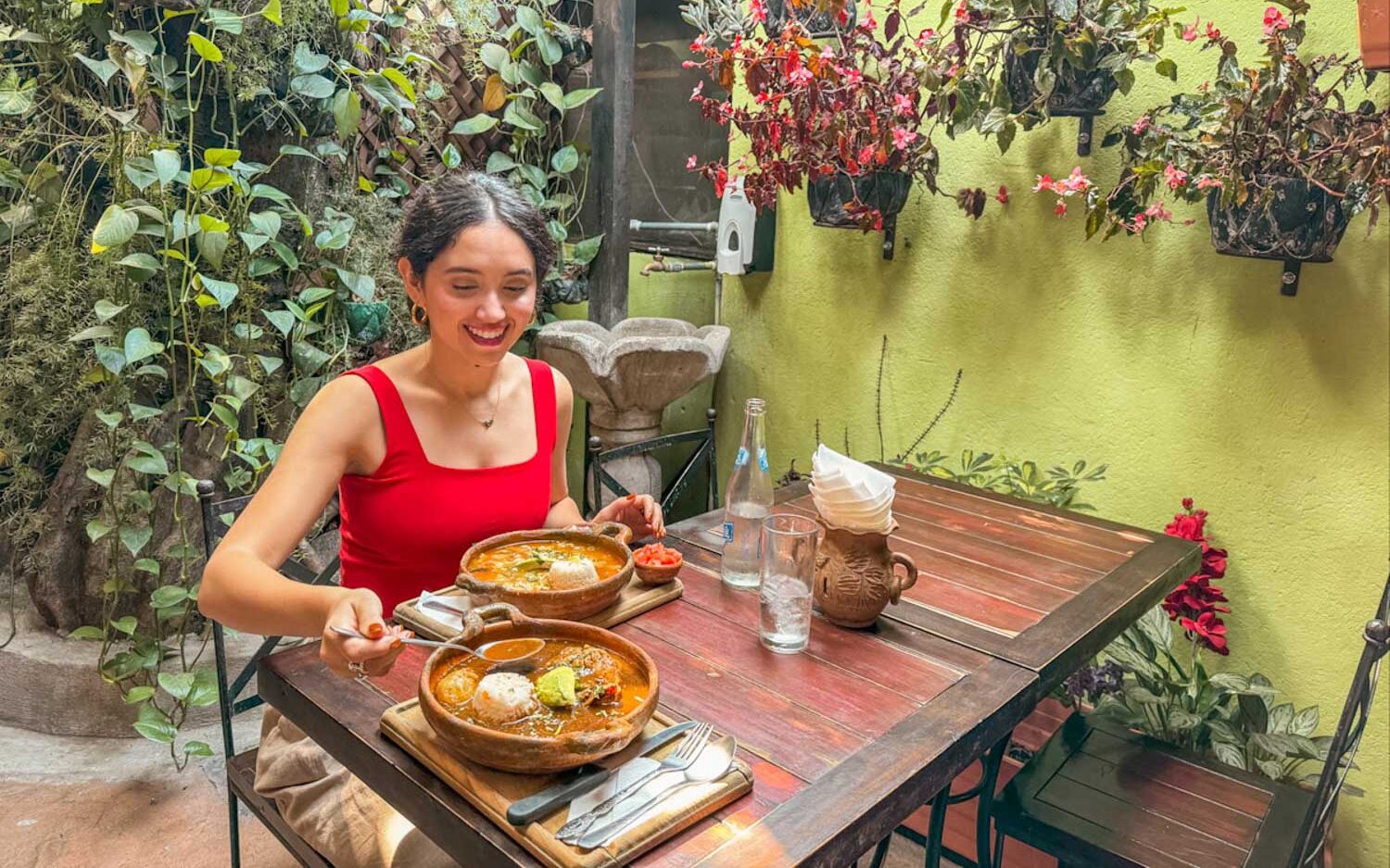 A woman sitting at an outdoor dining table with bowls of Guatemalan food