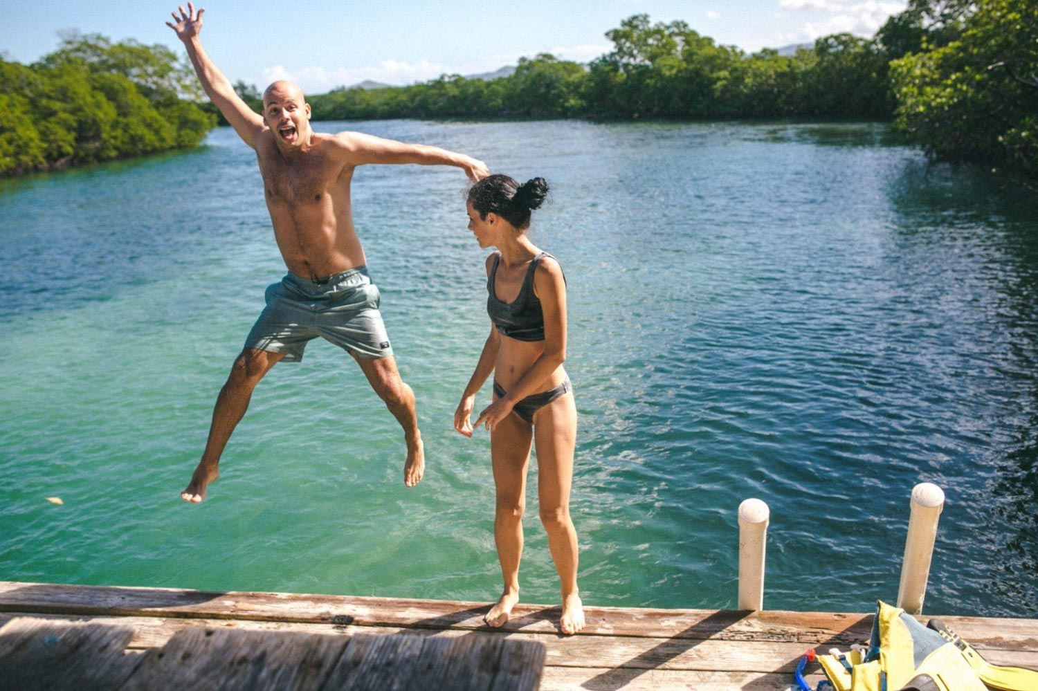 A man and a woman jumping into water in the Dominican Republic.