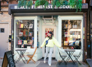 A woman standing at the outside entrance of Cafe Con Libros in Brooklyn, NYC.