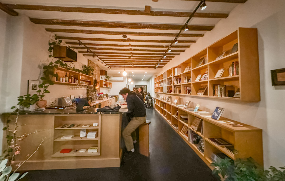 A New York City bookstore bar with wooden furniture and indoor plants.