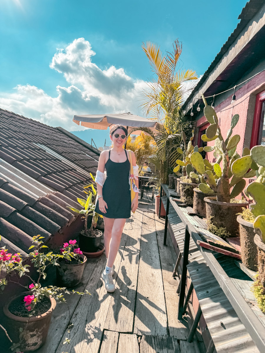 A woman standing on a rooftop decorated with plants in Antigua, Guatemala.