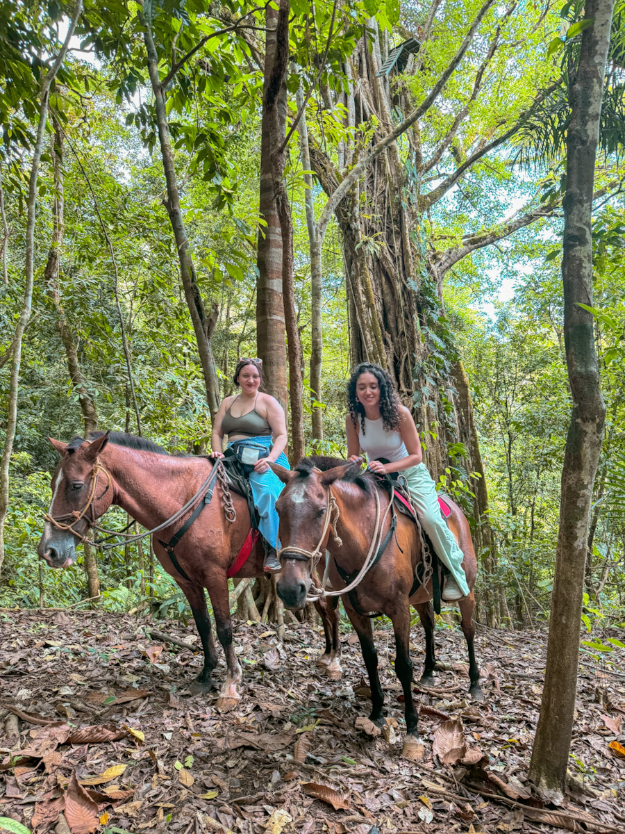 Two women riding horses in the forest, one of the things to do in Puerto Jimenez, Costa Rica.