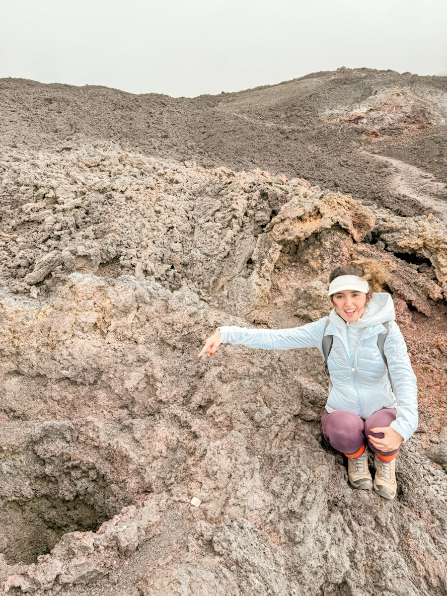 A woman pointing at a hole on Volcano Pacaya.