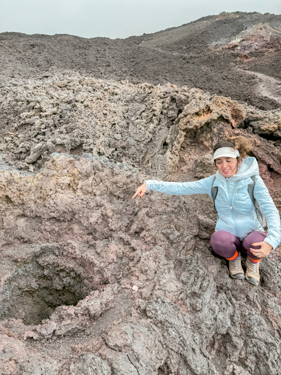 A woman pointing to a hole in a volcano in Antigua, Guatemala.