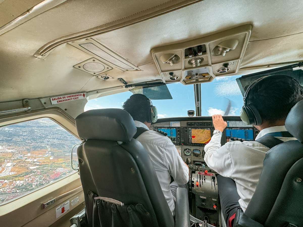 Two pilots flying an airplane above land.