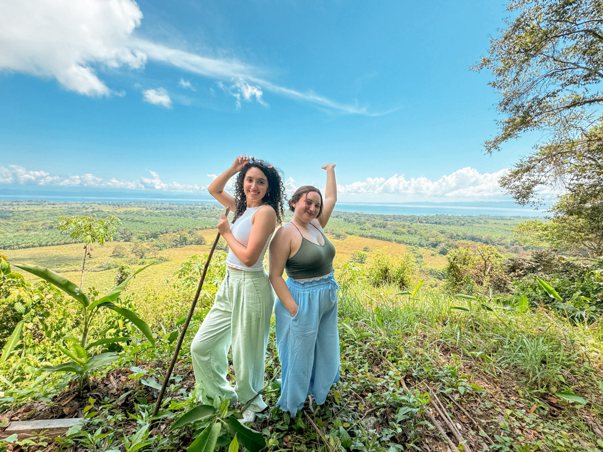 Two woman standing in front of a wide land in Costa Rica.