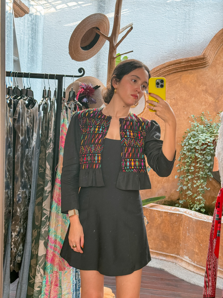 A woman wearing a dark gray dress taking a mirror selfie.
