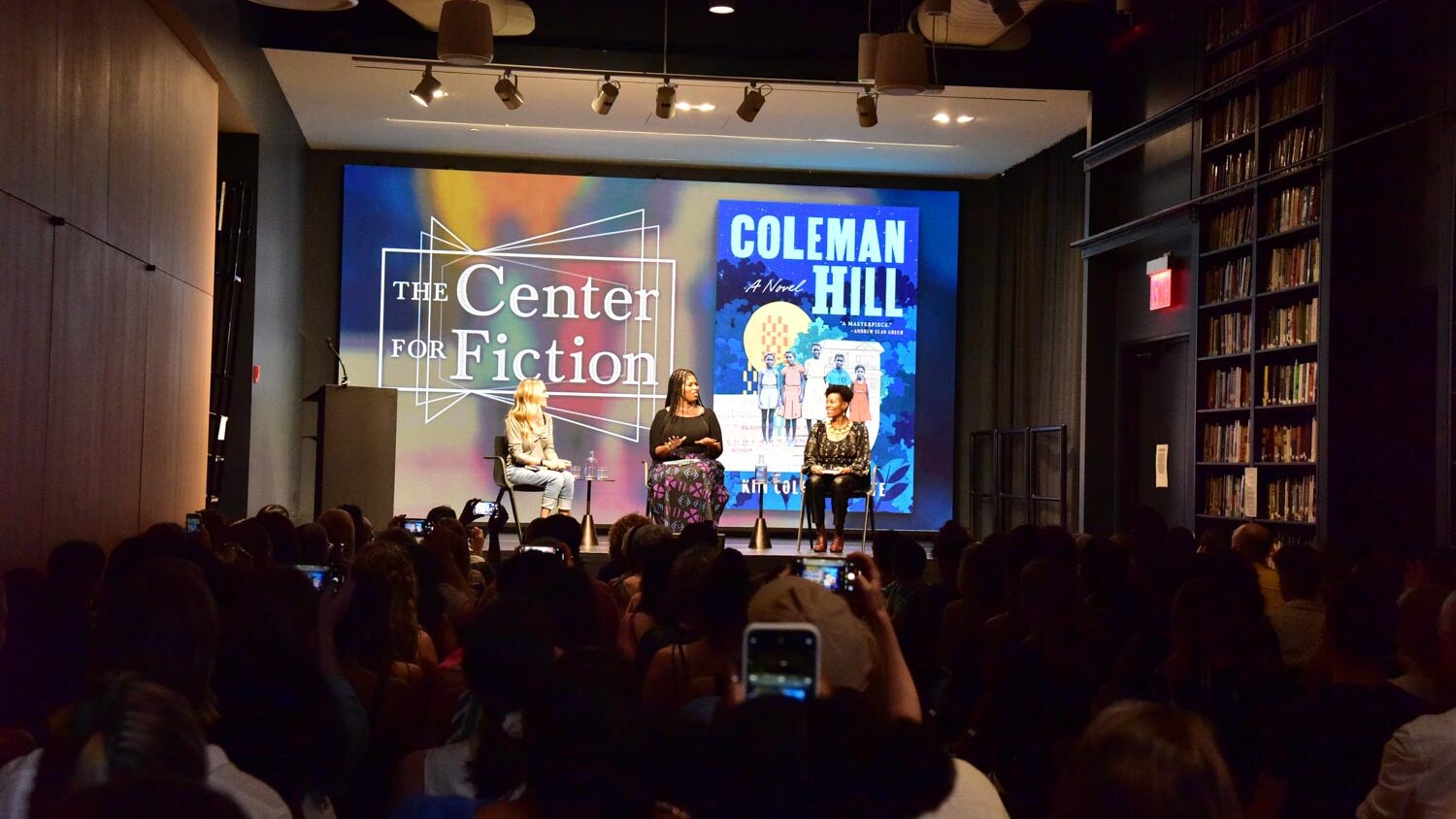 The crowd and three people on the stage at a book event in one of the independent bookstores in New York City.