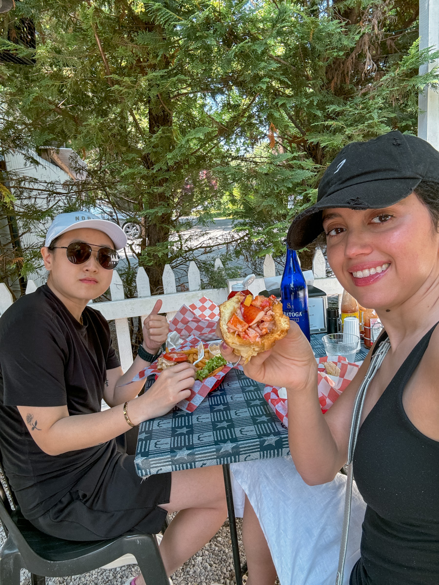 Two people in black clothes eating hot buns and tacos in Montauk.