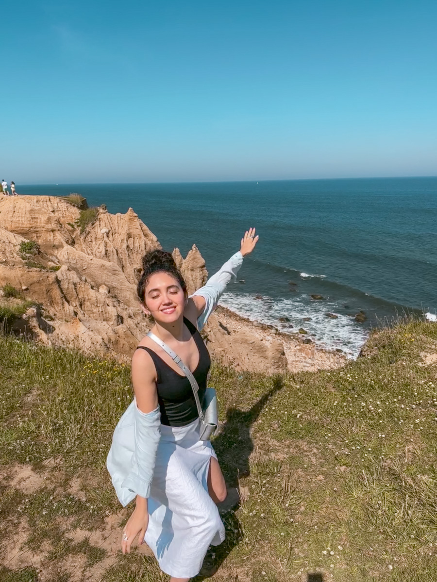 A woman posing at a cliff with the sea behind her in Montauk, Long Island day trip.
