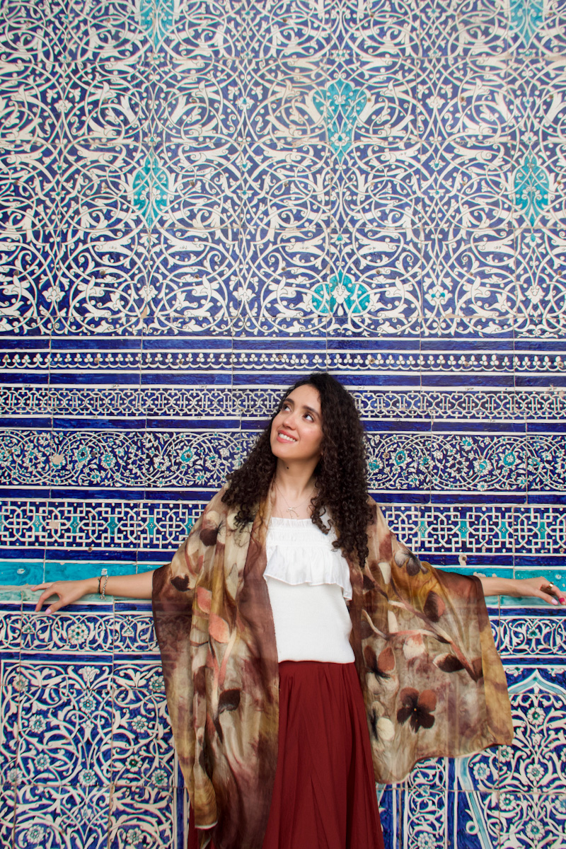 A woman standing in front of a wall with blue tile work in Khiva.