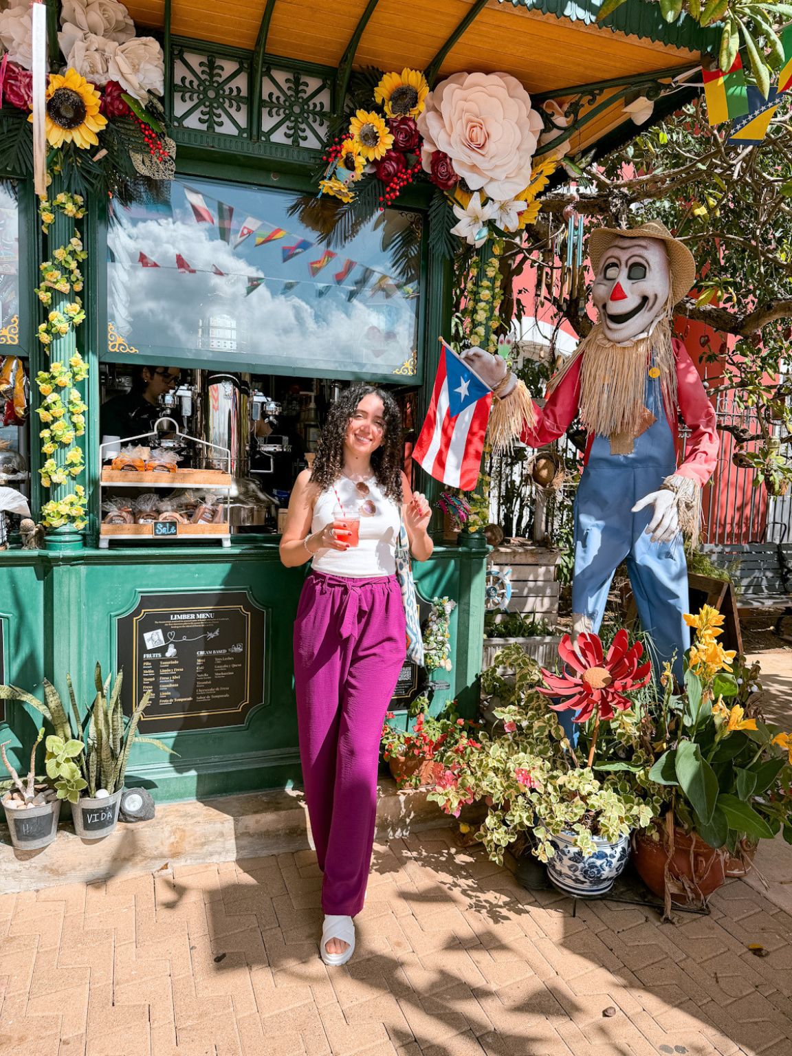 A woman standing and holding a drink in front of a food stall in Puerto Rico.