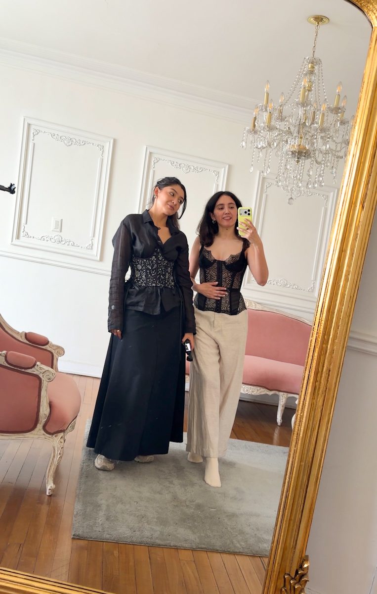 Two women in fashionable clothes taking a mirror selfie inside a boutique in Bogota.