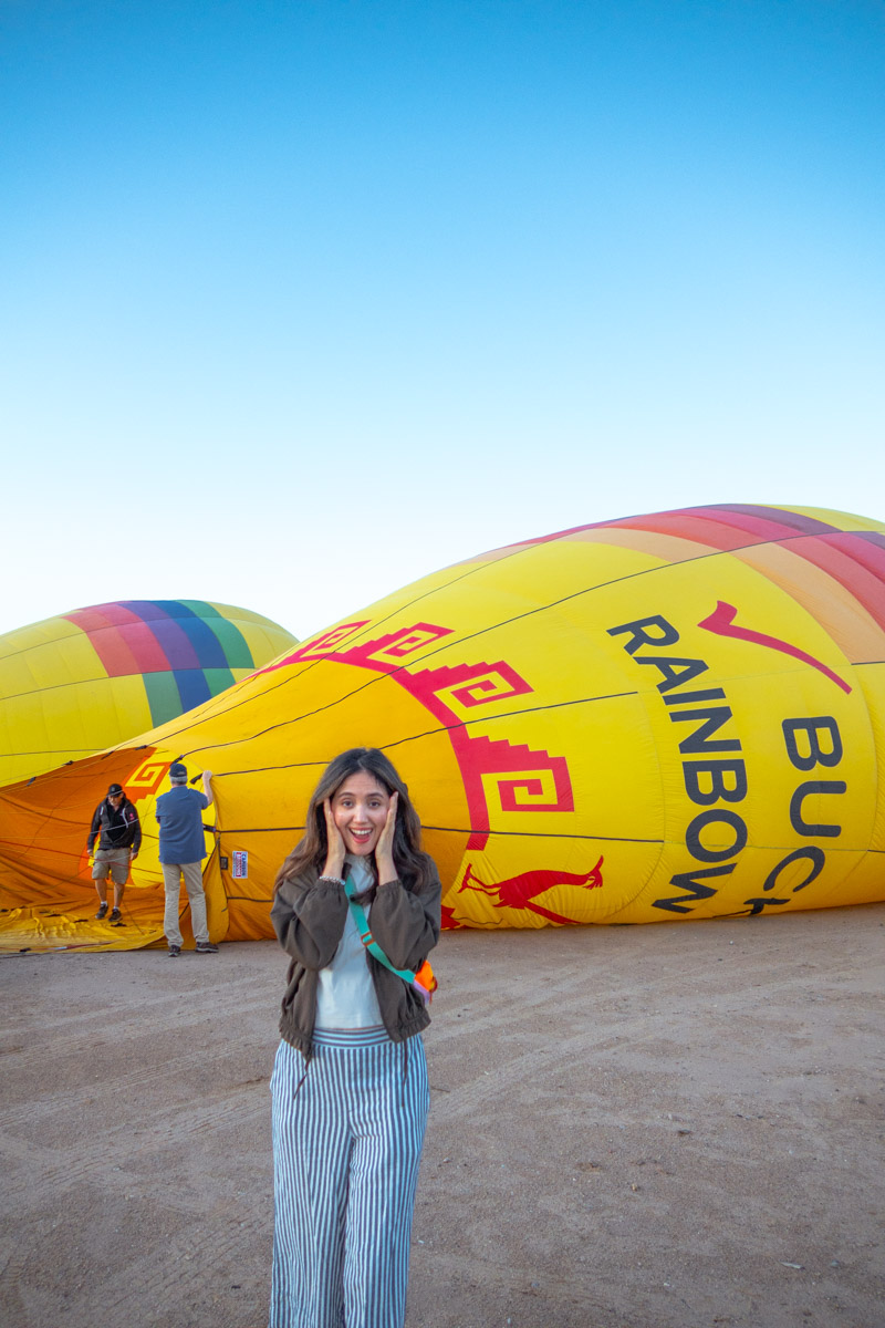 A woman with a surprised expression in front of hot air balloons in Albuquerque, New Mexico.