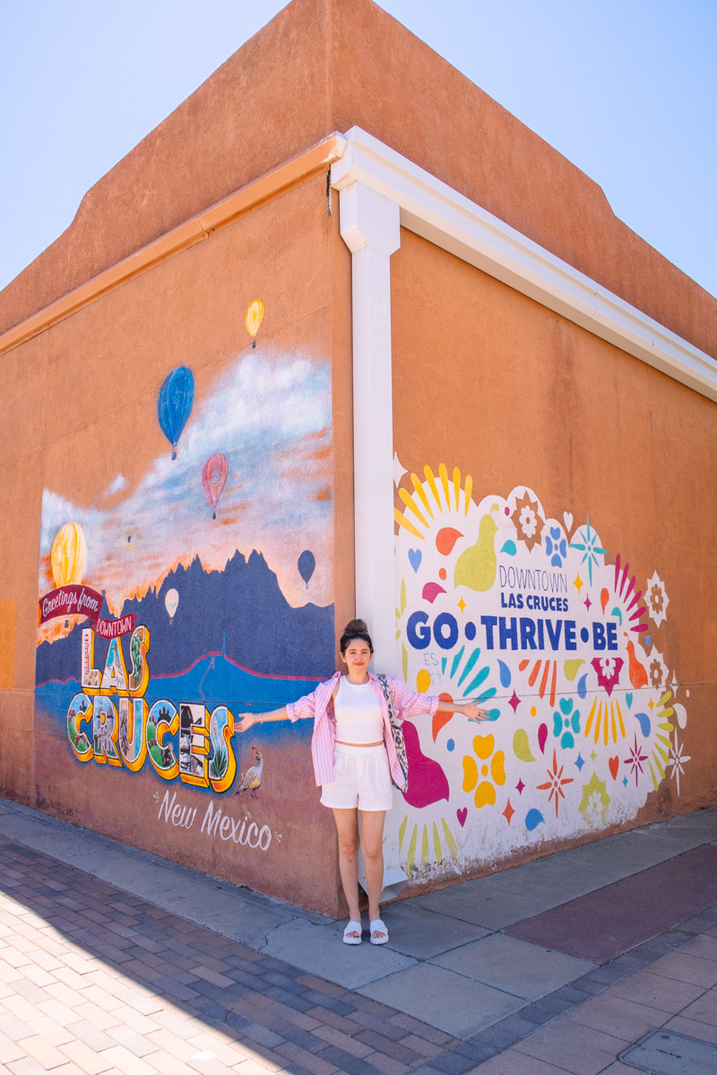 A woman standing on a street wall corner with wall art in Las Cruces, New Mexico.