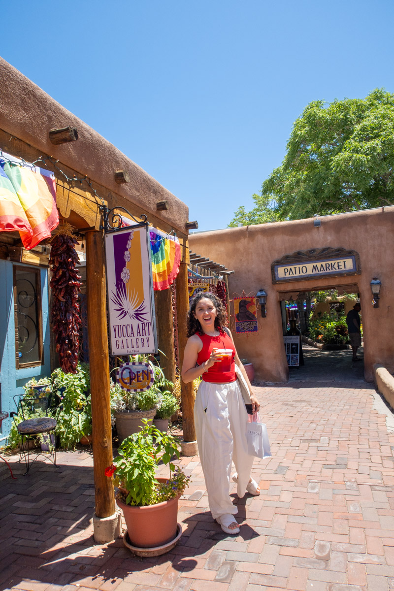 A woman outside a shop in Old Town Albuquerque with brick floors and colorful outdoor decor.