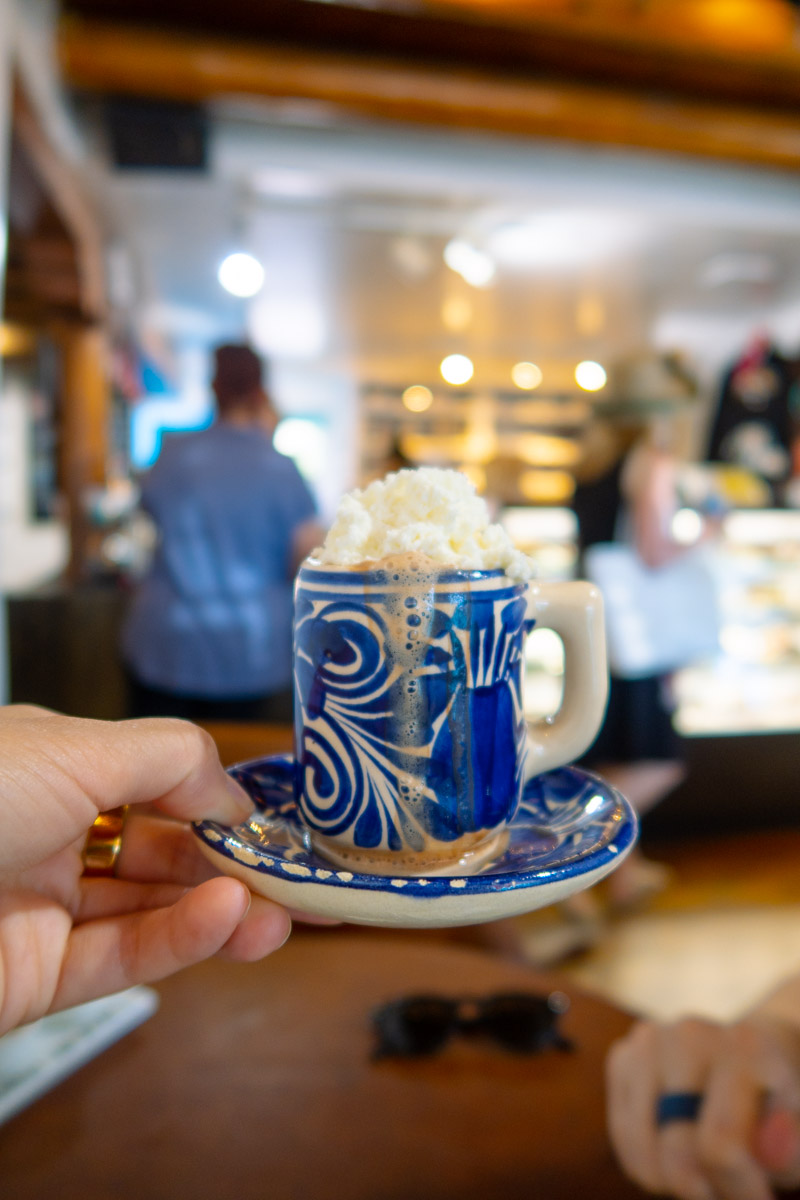 A cup of hot chocolate with whipped cream in a blue ceramic cup.